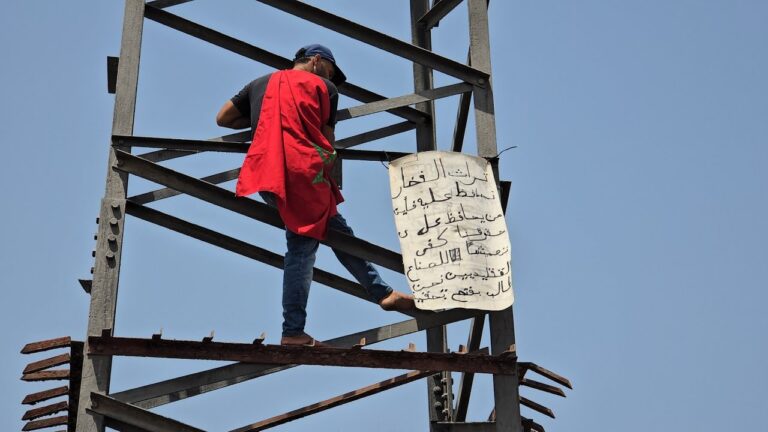 صانع تقليدي يحتج فوق عمود كهربائي